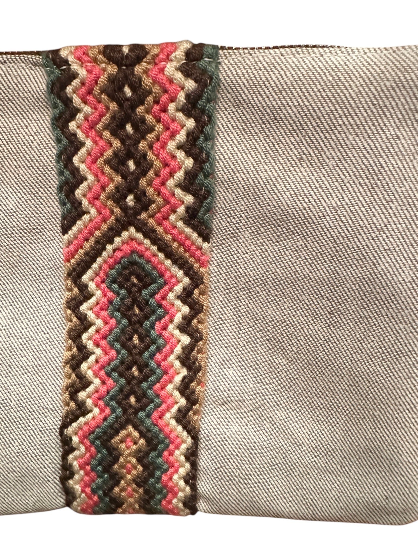 Gray clutch with a colorful zigzag patterned strap on a white background