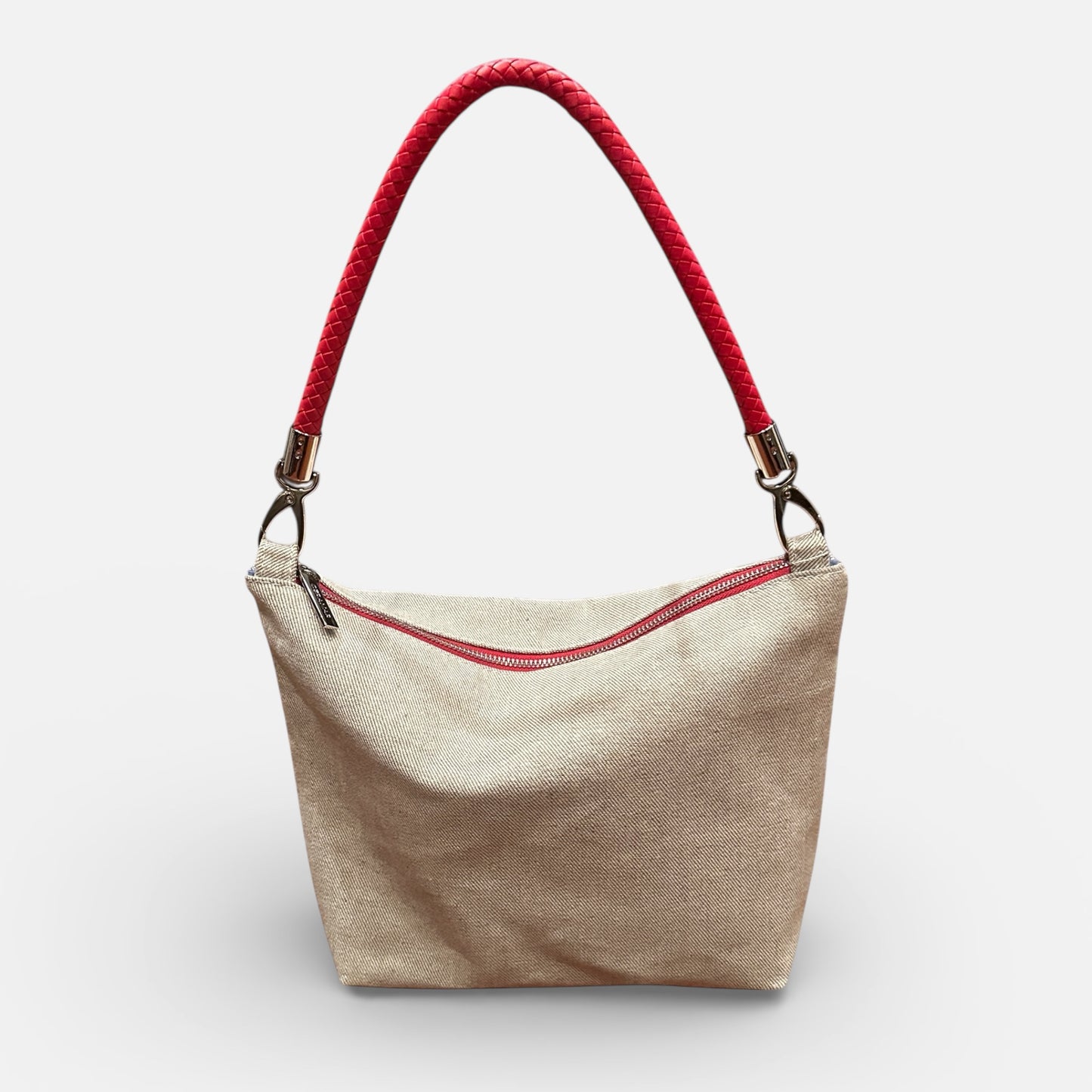 Beige handbag with red zipper and handle on a white background