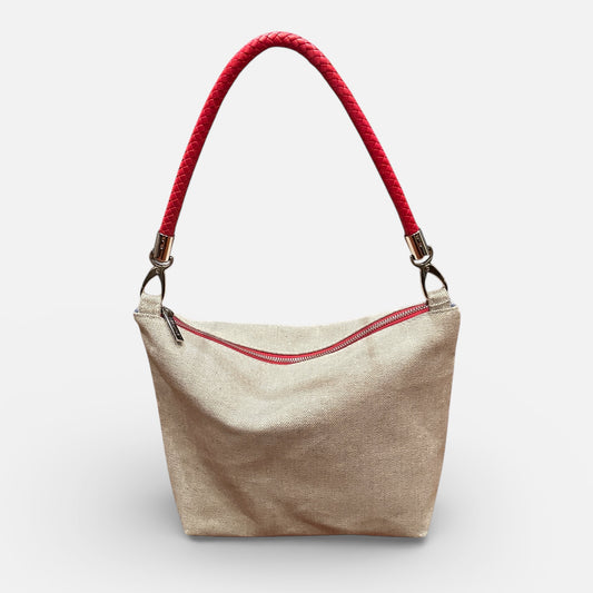 Beige handbag with red zipper and handle on a white background