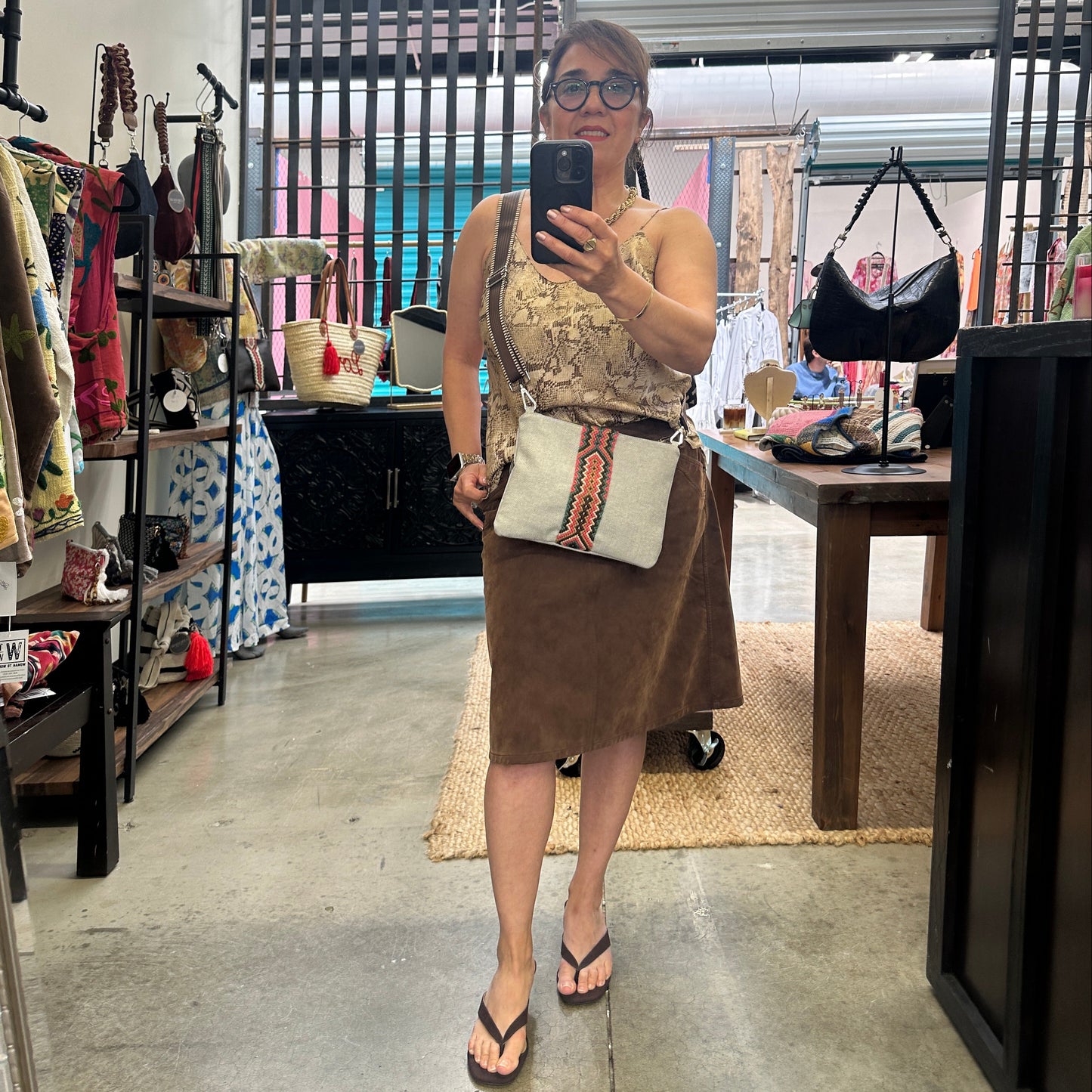 Woman standing with denim crossbody bag.