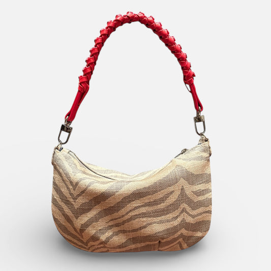 Handbag with zebra pattern and red handle on a light gray background