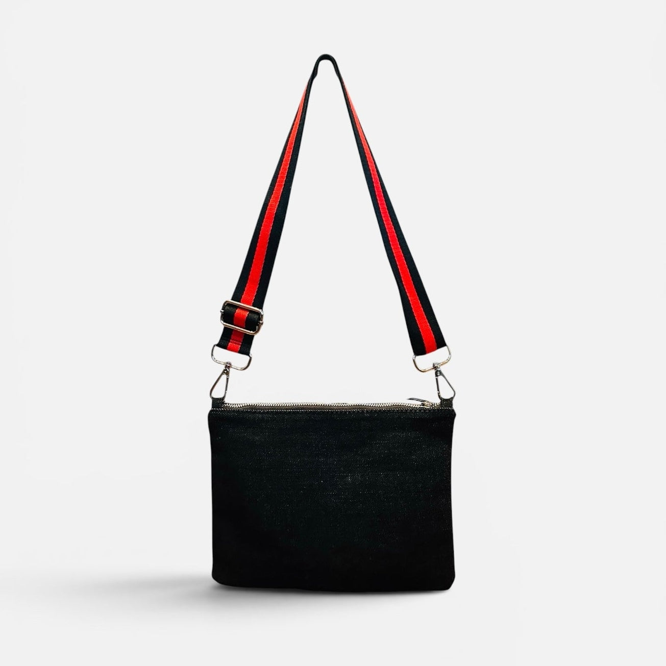 Black handbag with a red and black strap on a white background
