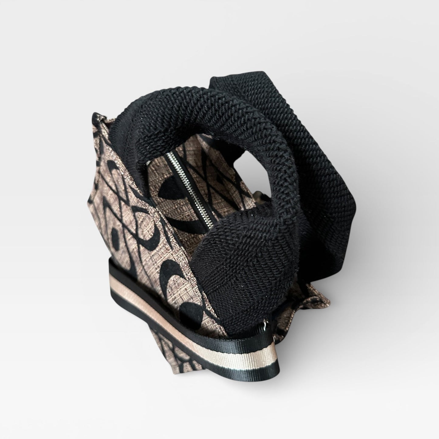 Black wedge sandal with patterned strap on a white background