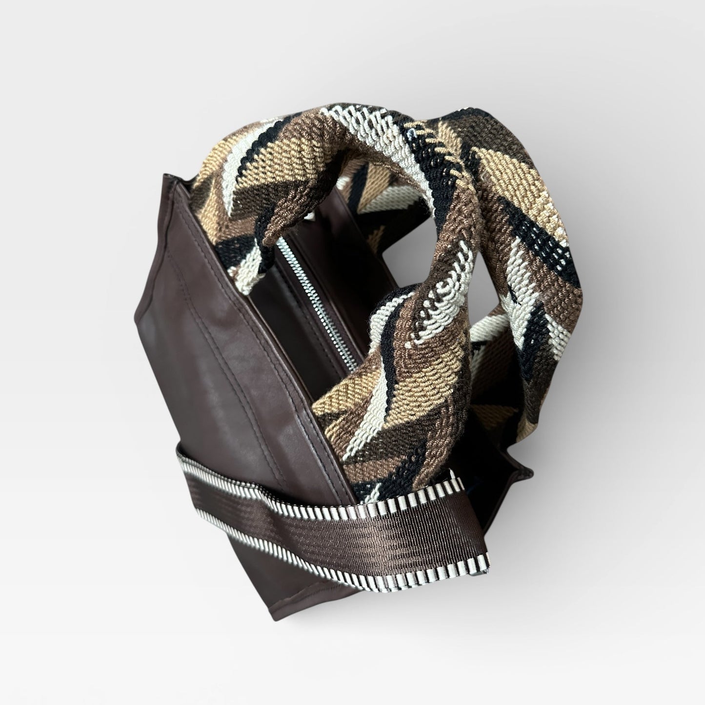 Brown leather wallet with a patterned flap on a light gray background