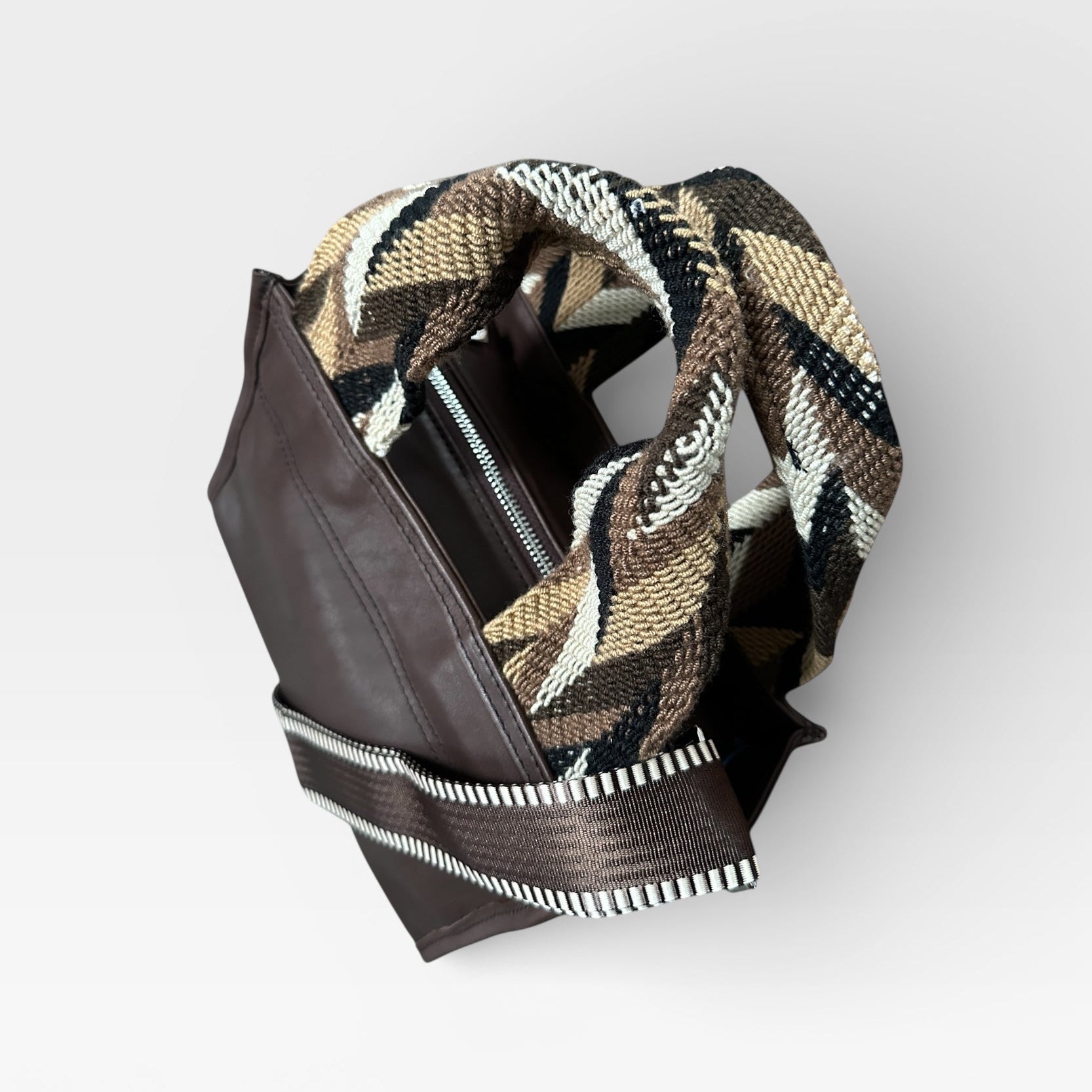 Brown leather wallet with a patterned flap on a light gray background