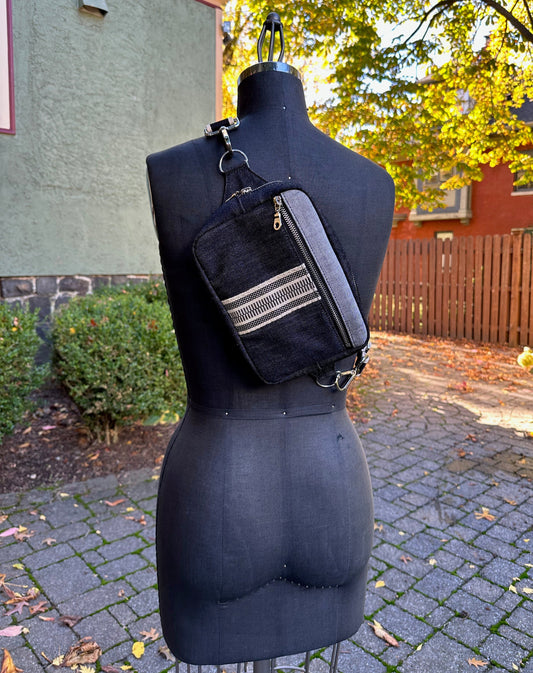 Unisex black denim sling crossbody bag with black & cream webbing.